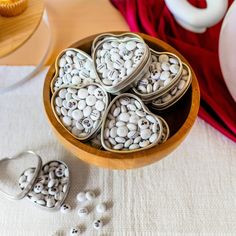 several heart shaped cookies sitting in a bowl on a table next to cupcakes