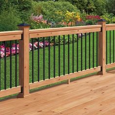 a wooden deck with black iron railings and green grass in the background on a sunny day