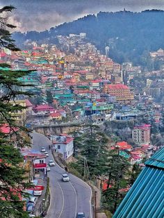 a view of a city from the top of a hill with mountains in the background