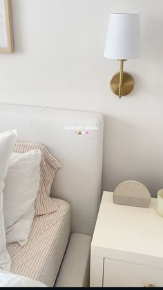 a white bed sitting next to a night stand with a lamp on top of it