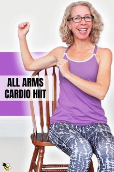 a woman sitting on top of a wooden chair with her arms up in the air