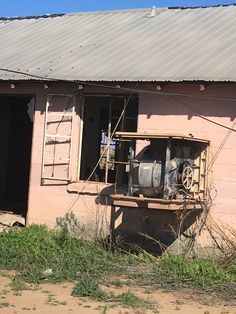 an old run down pink building with a broken window and door on the outside side