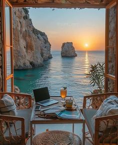 an open window overlooking the ocean with a laptop computer on it and a cup of coffee