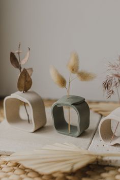 three small vases sitting on top of a table next to each other with plants in them