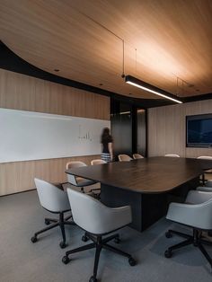 a conference table with white chairs and a flat screen tv mounted on the wall behind it