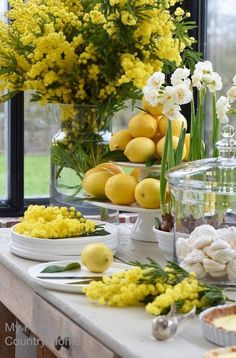 the table is set with lemons, flowers and other foodstuffs on it