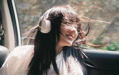 a woman sitting in the back seat of a car with headphones on her ears