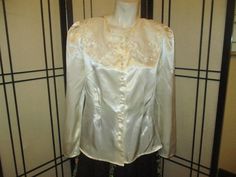 "Soft and feminine ivory satin blouse by Milani Petite is @ 1980's. 100% polyester. Hand wash or dry clean.  Button down with faux pearl buttons The wide collar is sheer with embroidery and faux pearls. Large shoulder pads. Fitted at the waist. Size 12. It measures 23\" long. 15 1/2\" across the top of the shoulders. 23 1/2\" sleeves. Laying flat seam to seam it's 20\" across under the arms, 16 1/2\" at the waist.  Practically like new. The only issue I can find is a tiny spot on the back side o Cream Satin Top For Formal Occasions, Cream Satin Tops For Formal Occasions, Formal Cream Satin Top, Spring Satin Blouse With Buttons, Satin Blouse With Buttons For Spring, Spring Wedding Button-up Blouse, Classic Formal Blouse With Pearl Buttons, Evening Satin Blouse With Buttons, Classic Fitted Blouse With Pearl Buttons