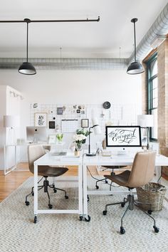 an office with two desks and chairs in front of a large window on the wall