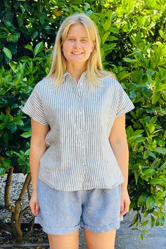 Material: 100% Linen. Description: Relaxed striped Linda linen shirt is easy going with shorts, skirt or jeans. Button down, cap sleeves and straight cut. ONE SIZE Color: Blue/White. Measurements: Bust: 45" Length: 24". Fits US size 6-12. Model is 5'8". Piironki Helsinki is Finnish lifestyle company established 1978. Their focus is relaxed, beautiful and cozy living. Vertical Stripes Shirt For Summer Day Out, Summer Shirt With Vertical Stripes For Day Out, Summer Day Out Shirt With Vertical Stripes, Spring Vertical Stripes Short Sleeve Shirt, Spring Striped Short Sleeve Shirt With Relaxed Fit, Pinstripe Button-up Shirt For Summer, Beach Tops With Striped Collar And Short Sleeves, Striped Linen Short Sleeve Top, Summer Pinstripe Shirt With Button Closure