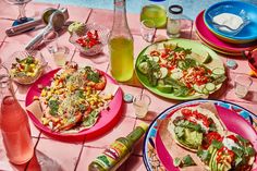 a table topped with plates filled with tacos and veggies next to drinks