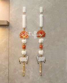 two white candles with red and gold decorations hanging from the wall next to each other