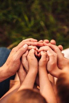 several people are holding their hands together in the middle of a circle on top of each other