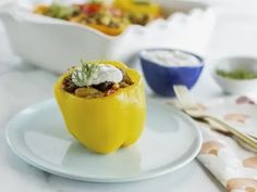 a yellow pepper stuffed with meat and vegetables on a white plate next to other dishes