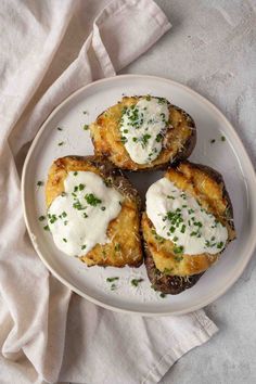 three stuffed mushrooms on a white plate topped with sour cream