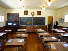 an empty classroom with wooden desks and chalkboard