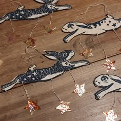 wooden ornaments with rabbits and stars on them sitting on a wood floor, hanging from strings