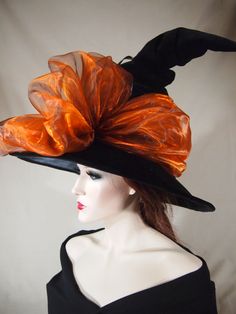 a woman wearing a black and orange hat with large flowers on it's side