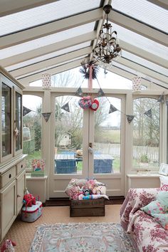 a sun room with lots of windows and furniture