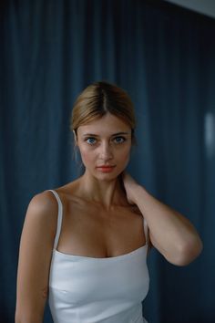 a woman in a white dress posing for the camera with her hand on her shoulder