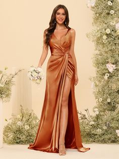 a woman standing in front of a floral backdrop wearing a brown dress with thigh high slit