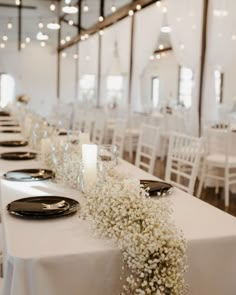 the table is set with black and white plates, silverware, and baby's breath flowers