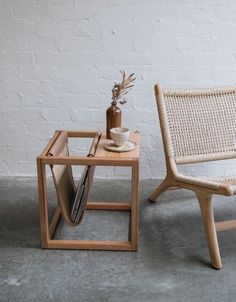 two chairs and a table in front of a white brick wall with a vase on it