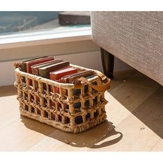 a wicker basket with books in it on the floor next to a window sill