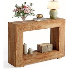 a wooden table with a vase on it and a lamp next to it, in front of a white background