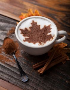 a cup of hot chocolate and cinnamon on a wooden table