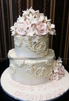 a three tiered cake with white frosting and pink flowers