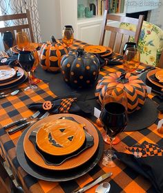 the table is set for halloween with pumpkins and black napkins on top of it