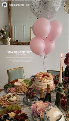 a table topped with pink balloons and plates filled with food next to a mirror on the wall