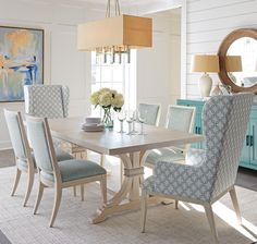 a dining room table with blue chairs and a white rug on the floor in front of it