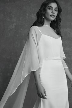 a woman wearing a white dress and cape