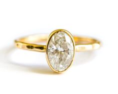 a yellow gold ring with an oval cut diamond in the center, on a white background