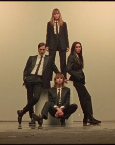 a group of people in suits and ties posing for a photo with one person sitting on the ground