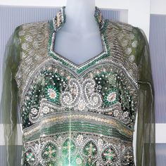 This rhinestone dress is a piece of art and definitely one-of-a-kind! It combines four kinds of fabric. The base of the dress is emerald green with silver floral design. It is covered with organza and has light cotton lining. The green velvet is used as a base for embroidery and the bottom of the dress to finish it up in a very original way. The velvet at the bottom has white machine stitches to enhance the overall design. The embroidery combination of various shapes of beads and sequins is stun Embellished Green Gown For Festivals, Traditional Green Embellished Dress, Fitted Embellished Festival Dress, Green Embellished Gown For Festivals, Fitted Embellished Gown For Festivals, Silver Dresses For Festive Occasions, Embellished Gown For Wedding And Festivals, Wedding Gown With Mirror Work In Green, Traditional Green Sequined Dress