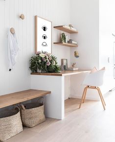 a wooden bench sitting in front of a white wall with flowers on top of it