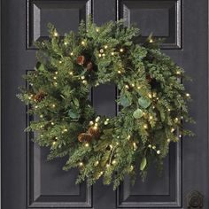 a christmas wreath is hanging on the front door with pine cones and evergreens around it