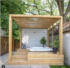 a hot tub sitting under a wooden pergol