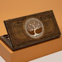 an intricately designed wooden box with a tree on the front and sides, sitting on top of a shelf