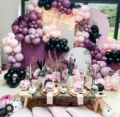 a table topped with lots of pink and black balloons