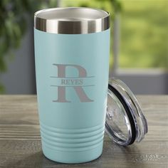 a light blue tumbler with the letter r on it sitting on a wooden table