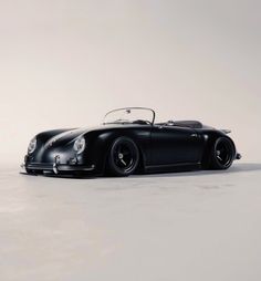 an old black sports car is parked on the floor in front of a white background