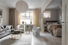 a living room filled with furniture next to a bed and a large white ball hanging from the ceiling