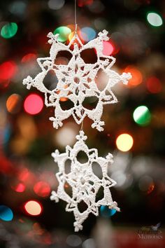 a crochet snowflake ornament hanging from a christmas tree with lights in the background