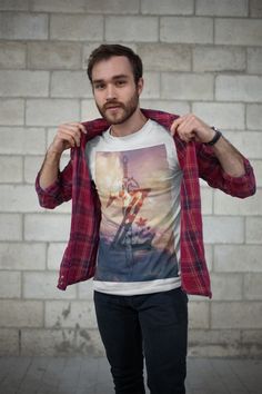 a man standing in front of a brick wall holding his jacket over his shoulder and looking at the camera