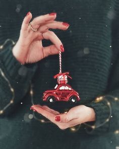 a woman holding a red car ornament in her hands