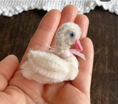 a tiny white bird with a pink ribbon on its neck sitting in someone's hand